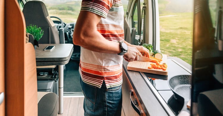 A man cutting vegetables with his RV kitchen essentials